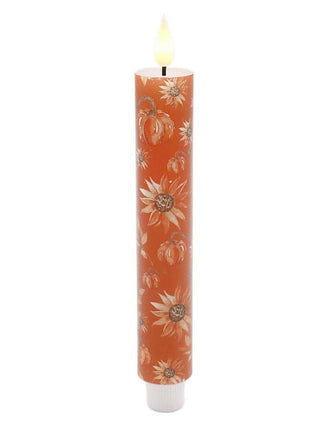 Rust orange LED candle with white floral pattern and glowing wick