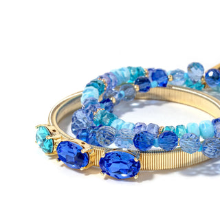Close-up gold-tone bracelet stack with layered blue and icy-clear faceted beads
