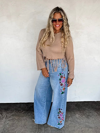 Light wash high-rise wide-leg jeans with floral embroidery along the legs