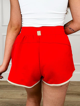 Red high-rise knit shorts with elastic waistband, center seam, ruffled hem