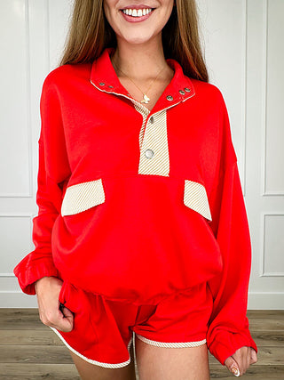 Red long-sleeve pullover top with white contrast placket and pocket-like panels