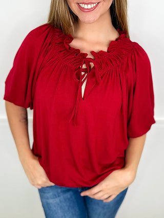 Wine red short sleeve blouse with ruffled neckline and tied bow front