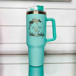 Teal mint gold-accent tumbler with clear lid, side handle, and front logo.