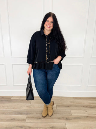 Black button up top with leopard print trim and a ruffle hem worn with dark wash skinny jeans and tan booties.