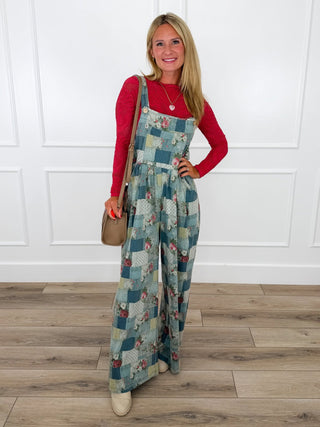 Blue and teal patchwork floral print overalls layered over a red lace top with cream booties.