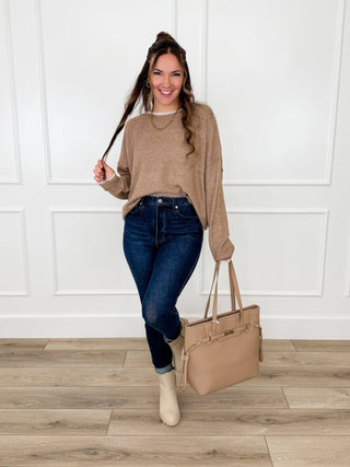Camel knit long sleeve sweater with an oversized drape worn with dark wash skinny jeans and cream booties.