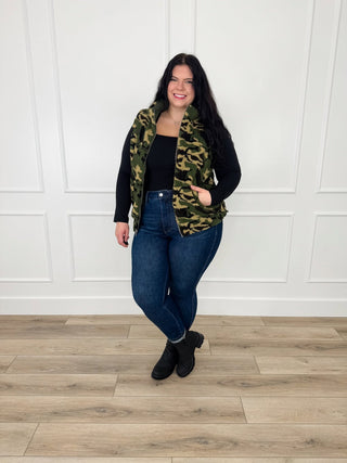 Camo sherpa reversible vest and blue denim jeans, with black boots
