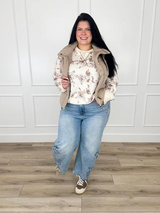 Cream floral knit top with tan puffer vest and light wash barrel-leg jeans