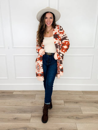 Cream southwestern print fuzzy knit duster cardigan styled over an ivory tank with dark wash skinny jeans and brown boots.