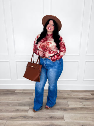 Red and cream rose floral sheer mesh top paired with flare jeans and a brown leather belt.