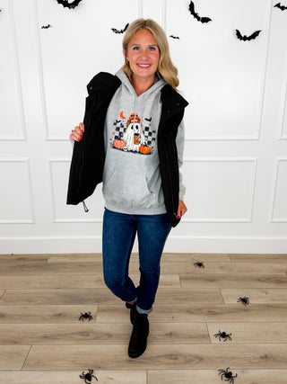 Model wears a grey Too Cool to Spook ghost graphic hoodie with a black puffer vest and Judy Blue Kyla jeans.