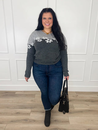 Grey color block knit sweater with cream daisies across the chest worn with dark wash skinny jeans and black booties.