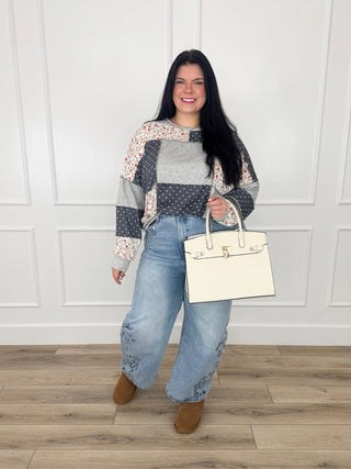 Grey patchwork knit top mixing floral print and polka dots worn with light wash embroidered wide leg jeans.