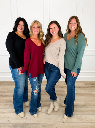 Four women wearing black, burgundy, oatmeal, and sage knit sweaters styled with different jean fits and booties.
