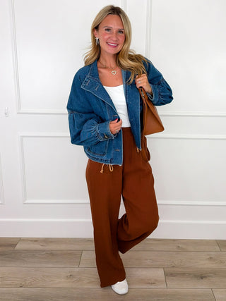 Medium wash cropped denim jacket with balloon sleeves, styled over a white cami with rust wide leg bottoms and white sneakers.