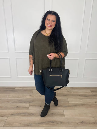 Olive textured open knit poncho top with short sleeves worn with dark wash skinny jeans and black booties.