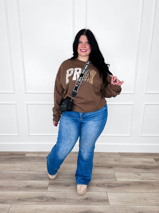 Brown Patchwork Pray graphic crewneck sweatshirt paired with flare jeans and tan booties.