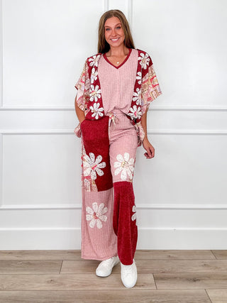 Pink and burgundy patchwork daisy print knit top and wide leg pants with white sneakers.