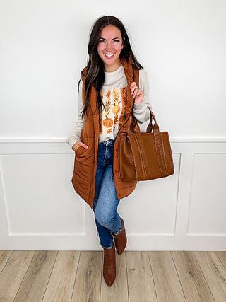 Brown puffer vest with faux leather tote bag, worn over blue jeans
