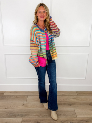 Rainbow striped button-up cardigan with long sleeves worn with dark blue jeans