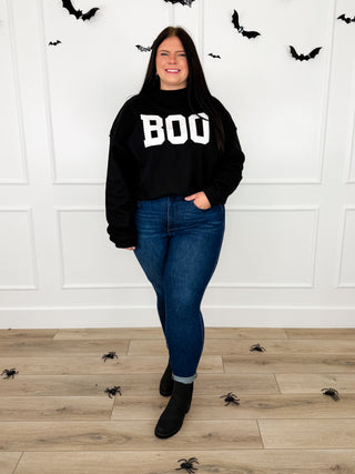 Model wears a black BOO reversible graphic mock neck sweatshirt with Judy Blue Kyla jeans and black booties.