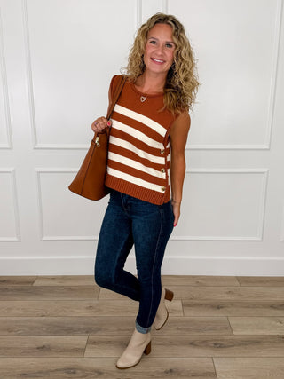 Rust and cream striped knit sweater vest with gold side buttons worn with dark wash skinny jeans and cream booties.