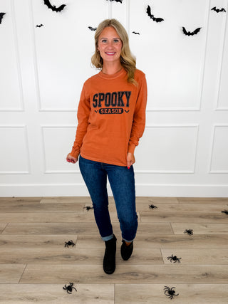 Model wears an orange Spooky Season graphic tee with Judy Blue Kyla jeans and black booties.