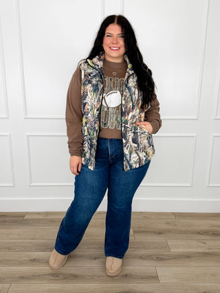 Women’s graphic tee and bootcut jeans with open patterned jacket, blue denim and tan top