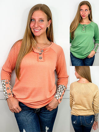 Peach knit long-sleeve henley top with button placket and leopard print cuffs