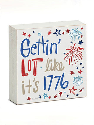 Wood block sign saying Gettin' Lot like it's 1776 with fireworks and star border