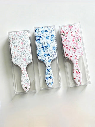 Set of floral detangling hair brushes in white, blue, and pink boxes