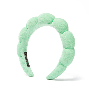 Mint green plush bubble headband with scalloped pads and black logo patch.