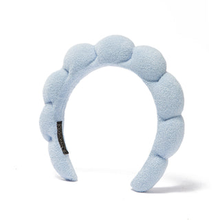 Light blue plush bubble headband with scalloped pads and black logo patch.