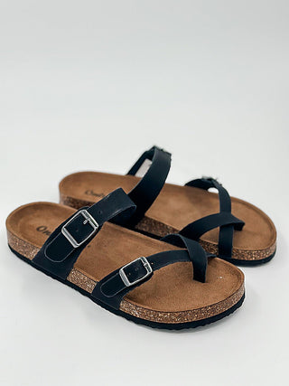 Black faux leather slide sandals with crisscross straps and two buckle closures
