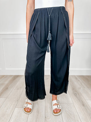High-rise black swim cover-up bottoms with tassel drawstring and wide-leg silhouette