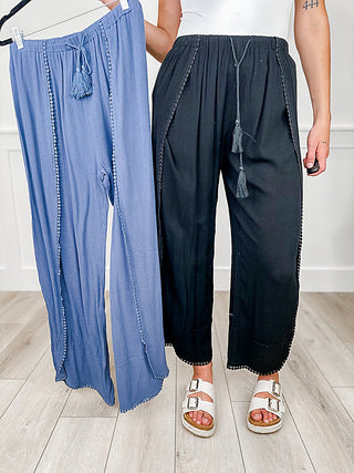 High-rise swim cover-up bottoms in black and denim blue, tassel drawstring, wide-leg