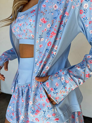 Light blue long sleeve zip-up jacket with red and pink floral print and ruffled hem
