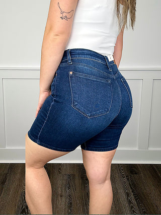 High-rise dark wash denim bermuda shorts, side view with front pocket