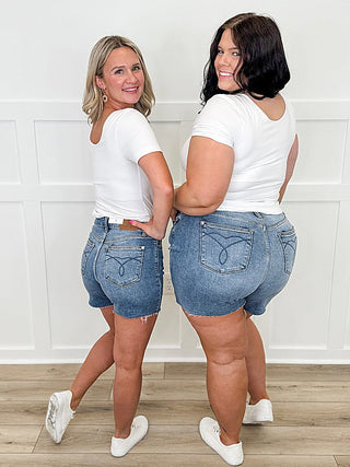 Medium-wash high-rise denim shorts with raw hem and clean, non-distressed look
