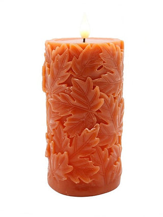 Orange LED pillar candle with embossed maple leaf pattern and lit wick