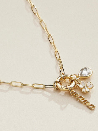 Gold charm necklace close-up with flower charm and crystal drop
