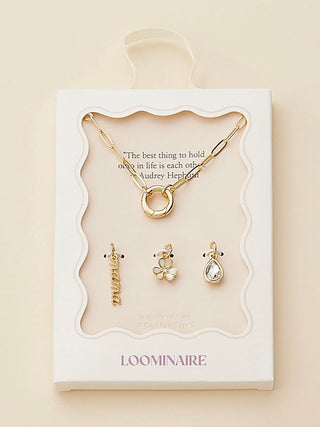 Gold charm necklace with multiple small dangling charms displayed on a card