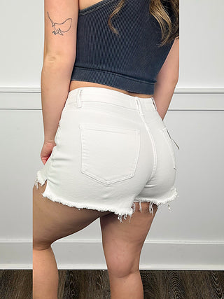 White high-rise denim shorts with frayed cuffs and five-pocket styling