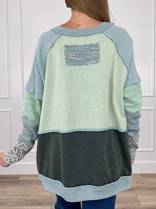 Colorblock long-sleeve top, back view with textured yoke detail and dark lower panel