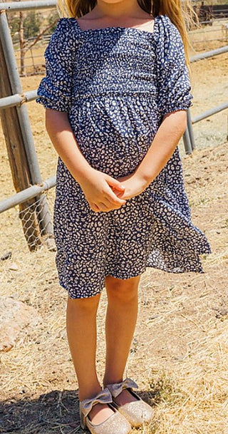 Navy and white patterned dress with square neckline, three-quarter puff sleeves, tiered hem