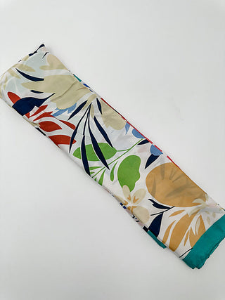 Multipurpose scarf with tropical leaf print in cream, blue, green, and tan; teal border