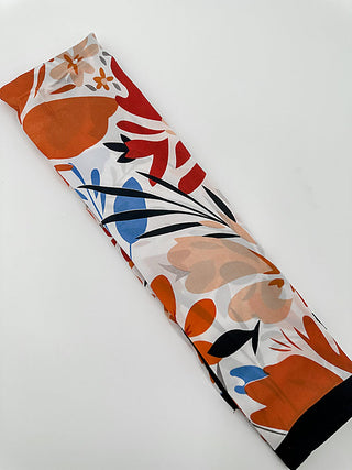 Multipurpose scarf in orange and white with abstract floral and leaf shapes; dark end