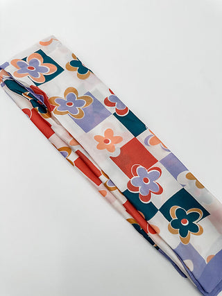 Multipurpose scarf with checkered pattern and flower motifs in red, blue, and purple