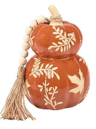 Rust orange pumpkin-shaped stoneware decor with white leaf pattern, bead stem, and tassel