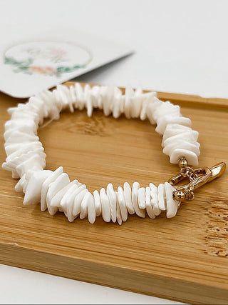 White beaded bracelet with gold clasp and small dangling charm